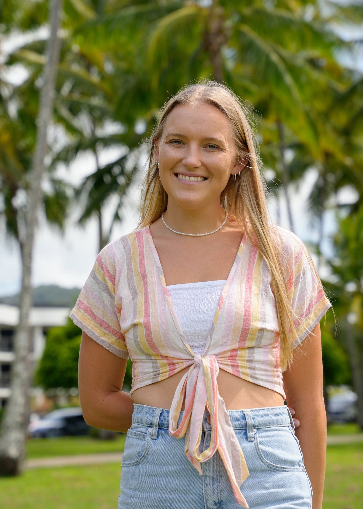 Claudia standing outdoors with palm trees in the background